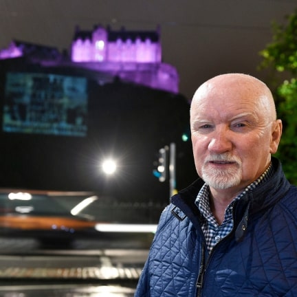 Sir Tom Hunter standing in front of Edinburgh Castle