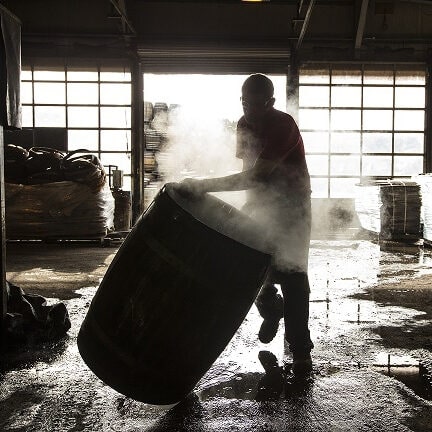 Distillery worker rolling barrel