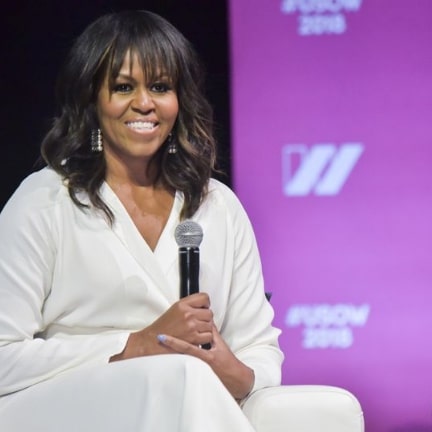 Michelle Obama smiling & holding microphone